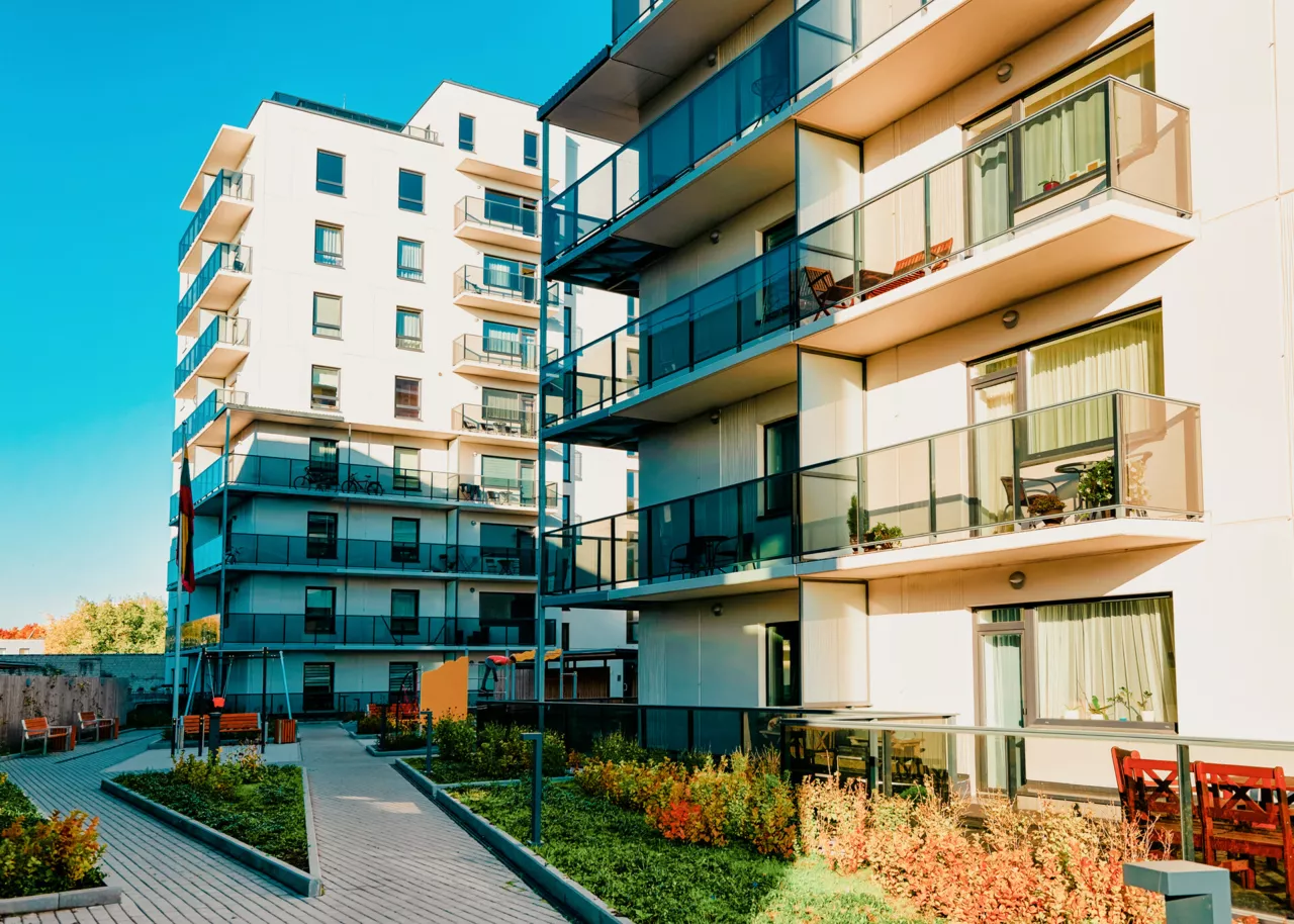 Bâtiment d'appartements moderne avec balcons et jardin commun.