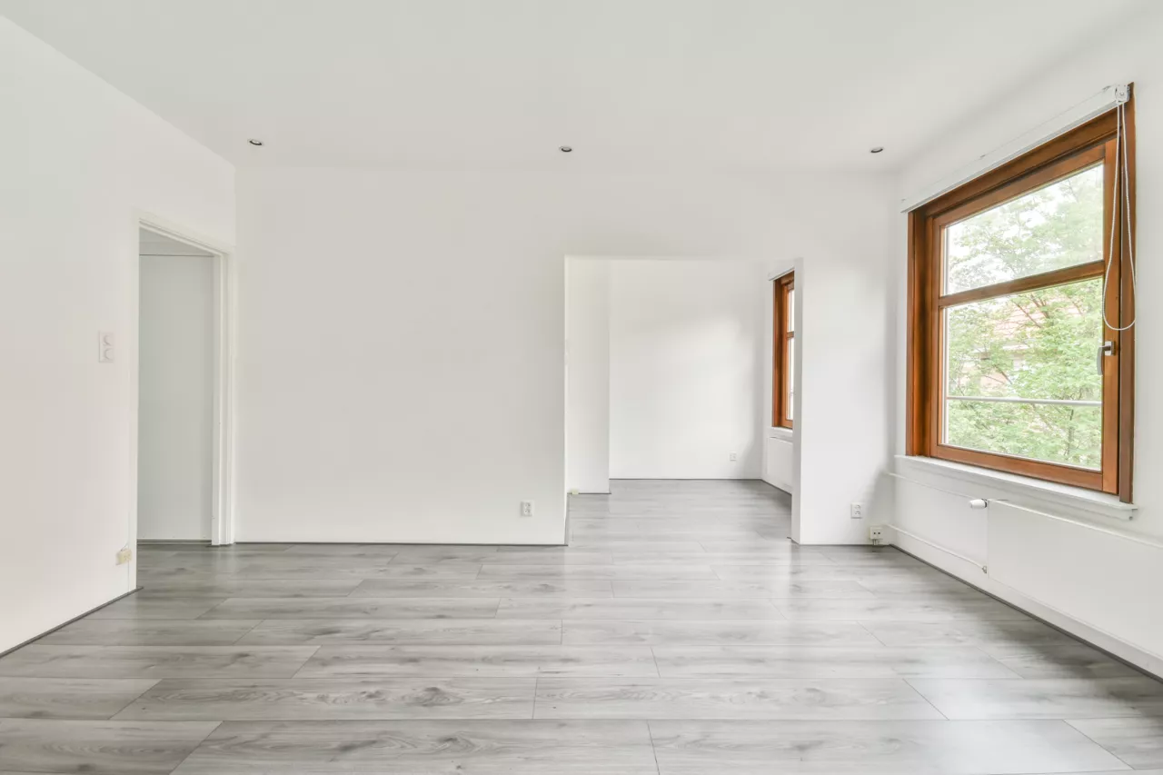 Intérieur vide d'une maison avec murs blancs et sol en bois gris.