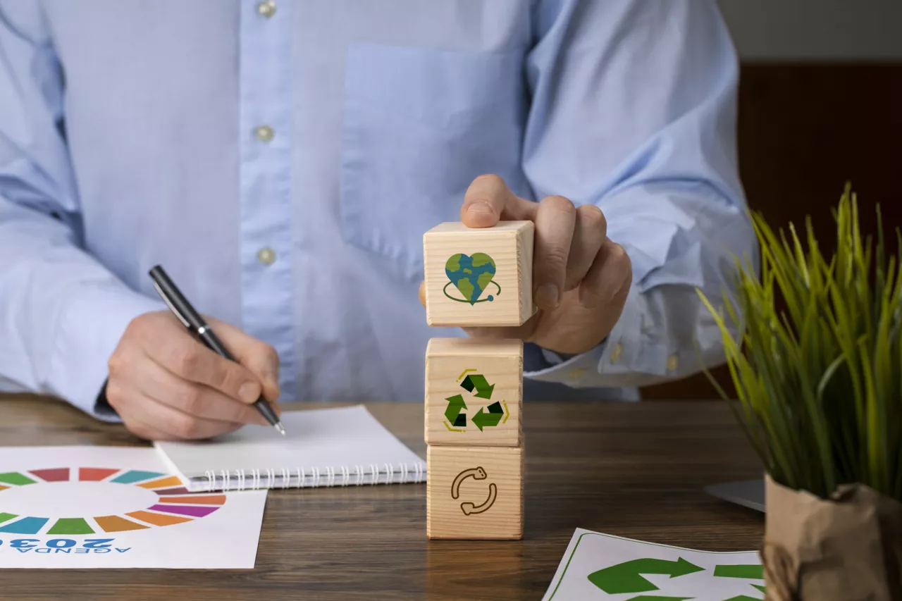 Main empilant des blocs de bois avec des symboles de recyclage et d'écologie.