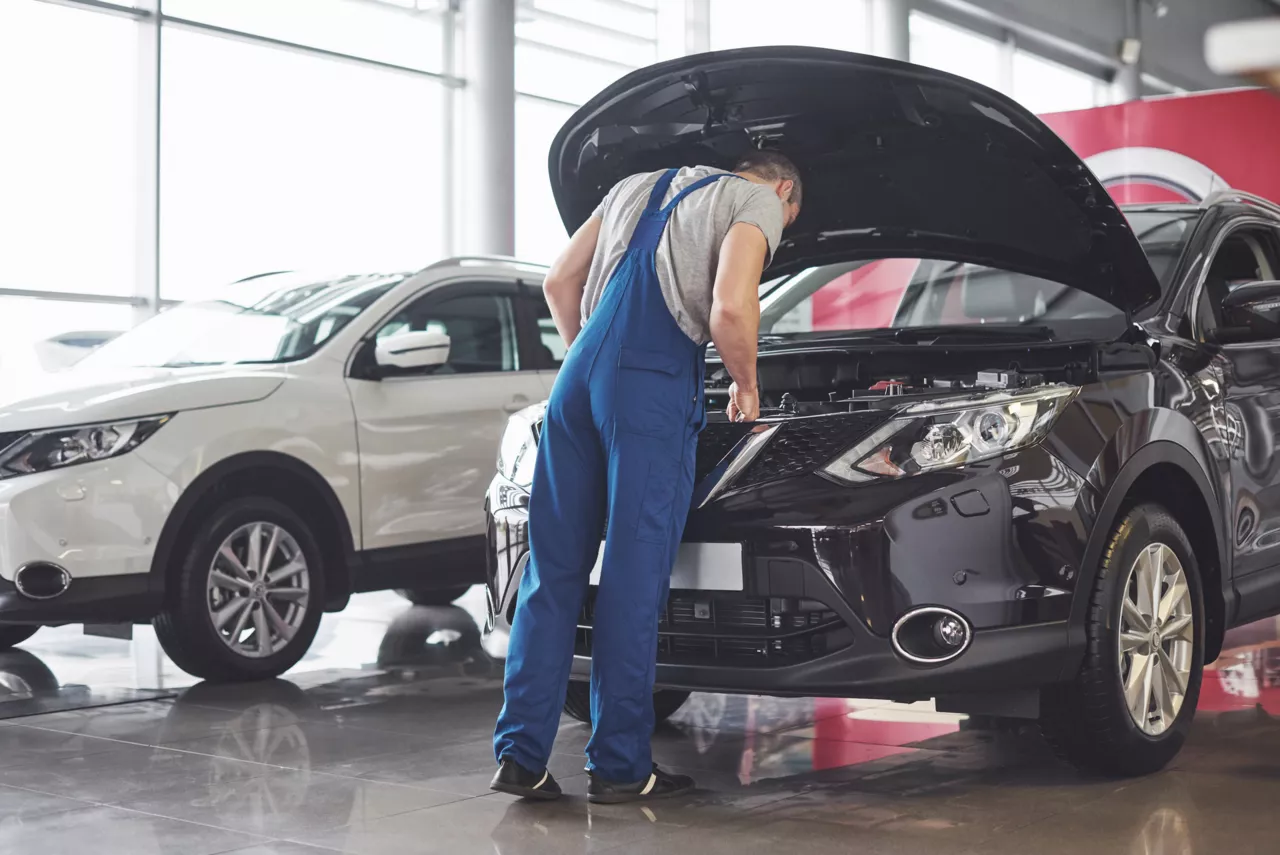 Mécanicien examinant le moteur d'une voiture dans un showroom.