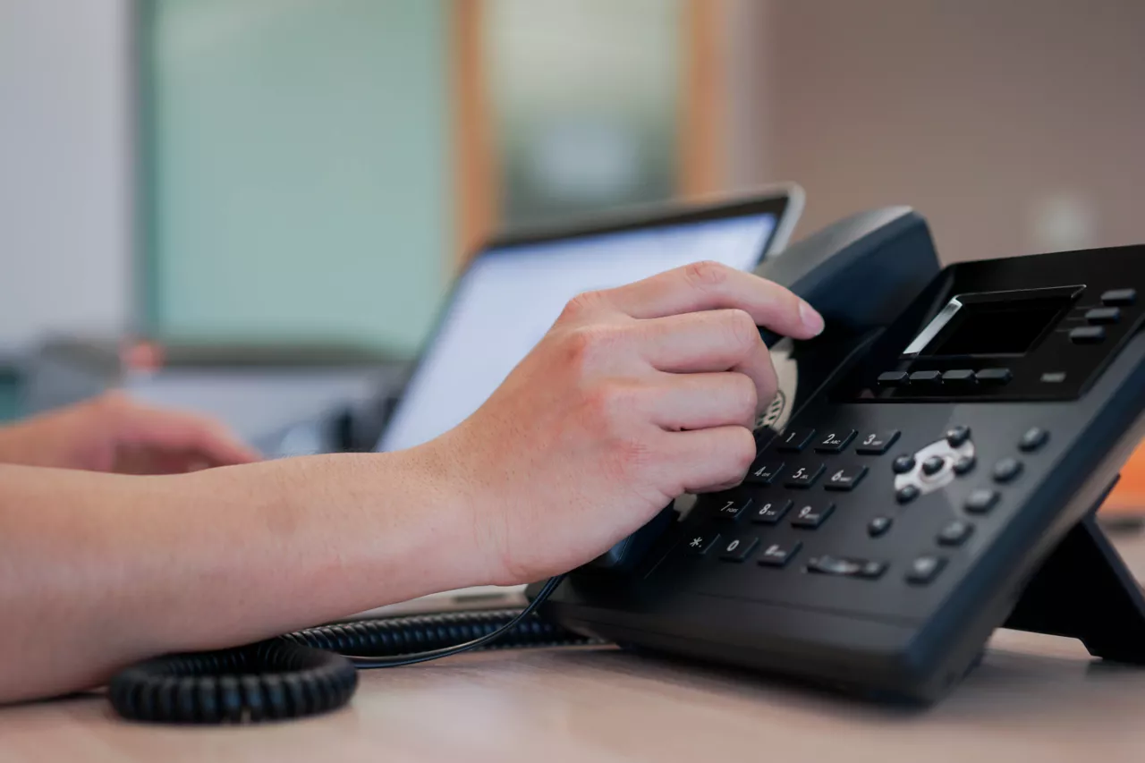 Main droite d'une femme tenant le combiné d'un téléphone