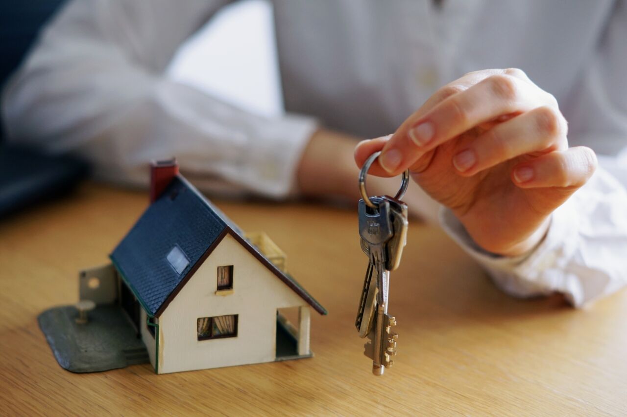 Main tenant des clés devant une maquette de maison, concept de propriété immobilière.