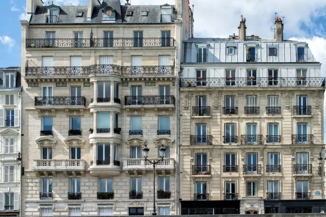 Façade détaillée d'un immeuble parisien traditionnel avec balcons en fer forgé.