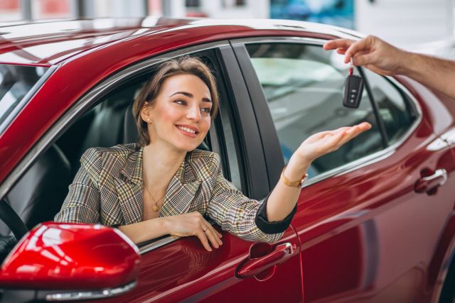 Femme souriante recevant des clés de voiture de la part d'un homme hors cadre.